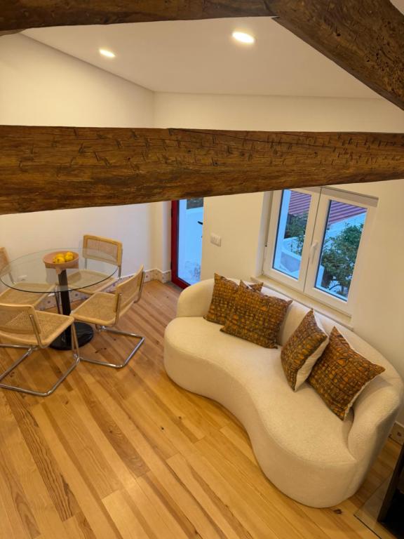 a living room with a white couch and a glass table at Casa da Ana - Casinhas com Alma in Torrão