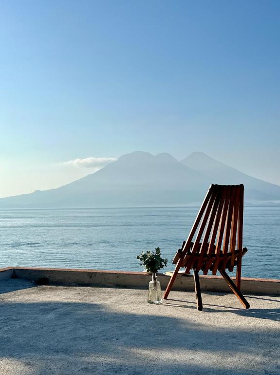a wooden chair sitting next to the ocean at Anzan Atitlan in San Marcos La Laguna