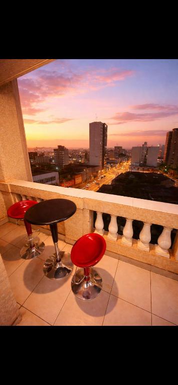 a balcony with two chairs and a table and a view of a city at Edifício Marília in Marília