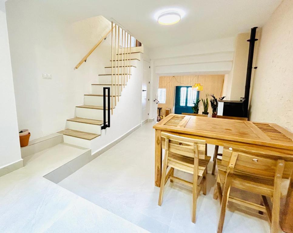 a dining room with a wooden table and stairs at La casa del pinsapo in Yunquera