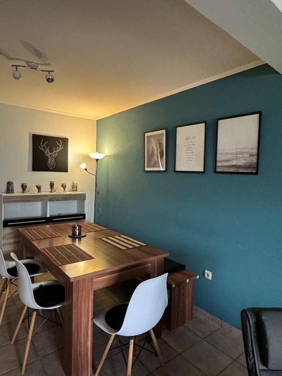 a dining room with a wooden table and white chairs at Ferienhaus am Rad- und Wanderweg in Nerdlen