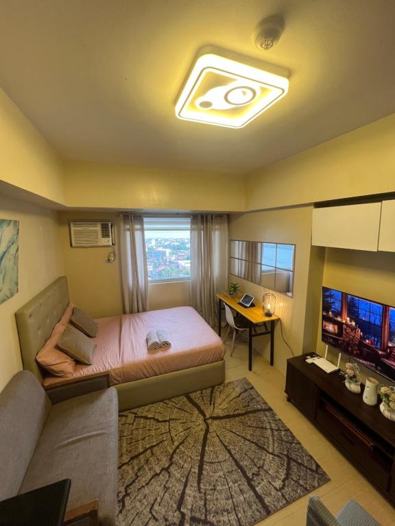 a bedroom with a bed and a couch and a television at Avida Tower 2 in Davao City