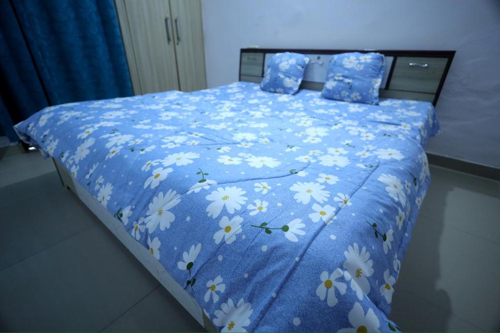 a bed with a blue comforter with flowers on it at Tajiva Stay in Agra