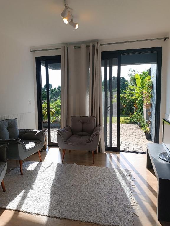 a living room with a couch and chairs and sliding glass doors at Refúgio Subterrâneo in Genuino Sampaio