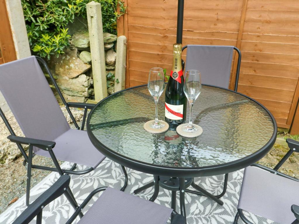 a glass table with two glasses and a bottle of wine at Min Y Cae in Cemaes Bay