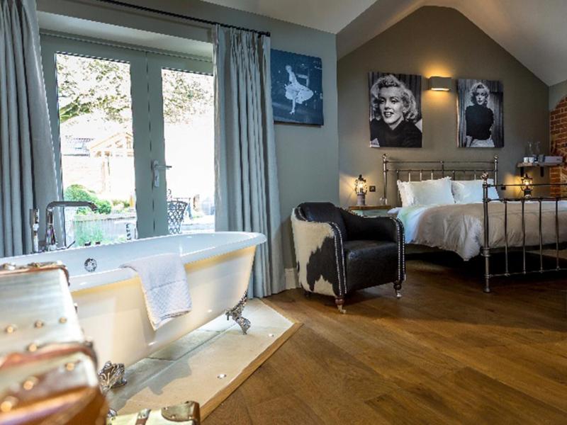 a bedroom with a tub and a bed and a chair at NoTwenty9 Bar and Restaurant in Burnham Market