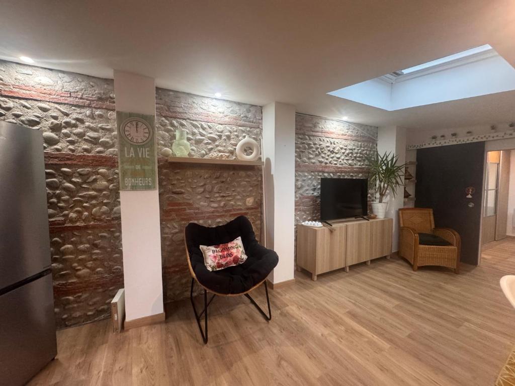 a living room with a chair and a television at Eaunes au Soleil in Eaunes