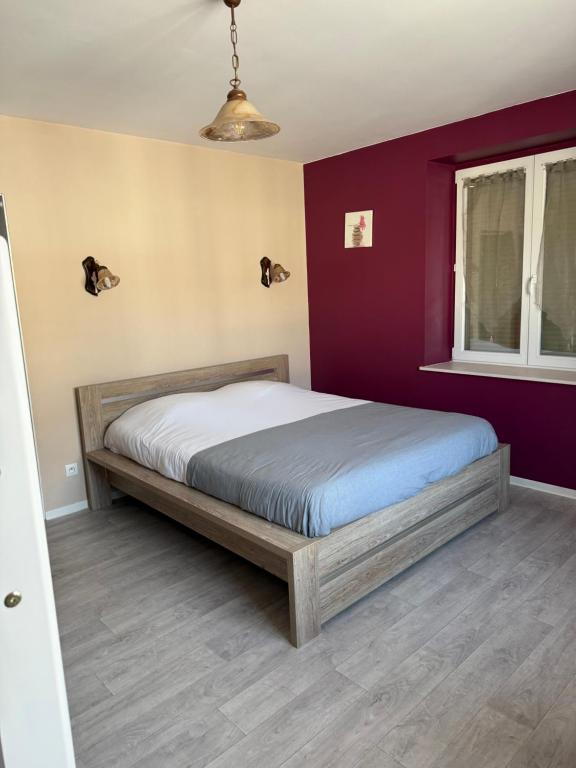 a bed in a bedroom with a purple wall at Chambre Double et Lits Superposés in Toul