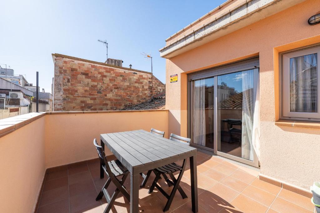 a balcony with a wooden table and chairs on a building at Hauzify I Apartaments Bellaire in Blanes