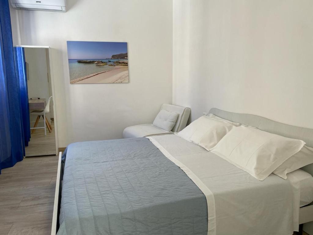 a white bedroom with a bed and a chair at Casa dei mulini in Favignana