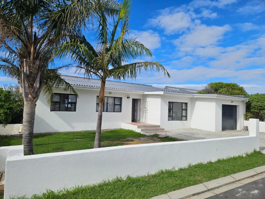 a white house with palm trees in front of it at Graatjie in Kleinmond