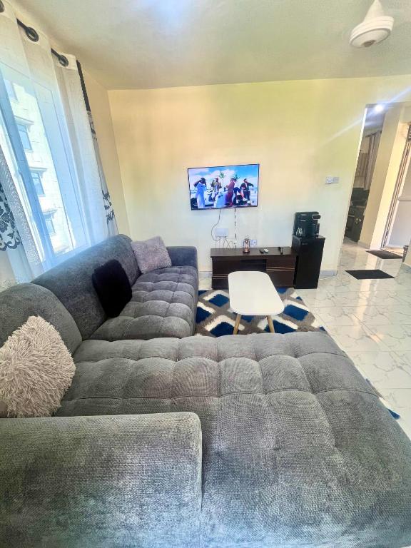 a living room with a large couch and a desk at Guest Favorite 1BDR with Washer, Netflix, Parking & Hot Shower 2547,96,065,022 in Mombasa