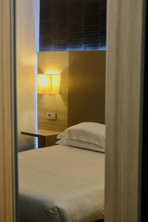 a bedroom with a bed and a table and a window at Hôtel L'Escale Coté Port in LʼÎle-Rousse