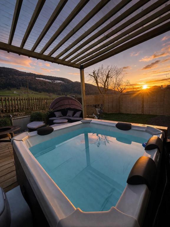 a hot tub under a pergola with the sunset in the background at Juralodgespa Chalet Emma in Courrendlin