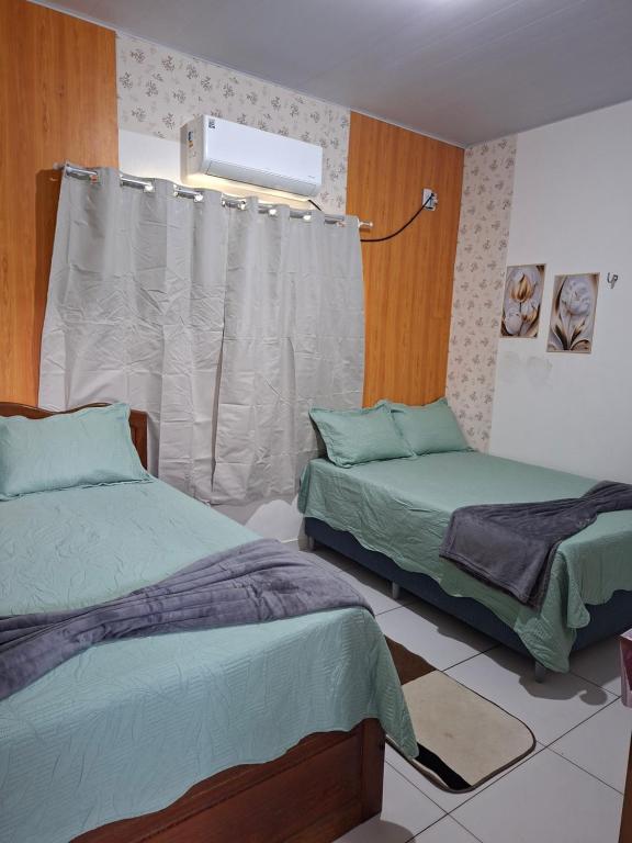 a bedroom with two beds and a window at cantinho da Raq,um quarto SUÍTE com ar condicionado duas camas de casal perto doAeroporto, UEPA, Rodoviaria, magueirao, UFPA,parque ambiental, in Belém