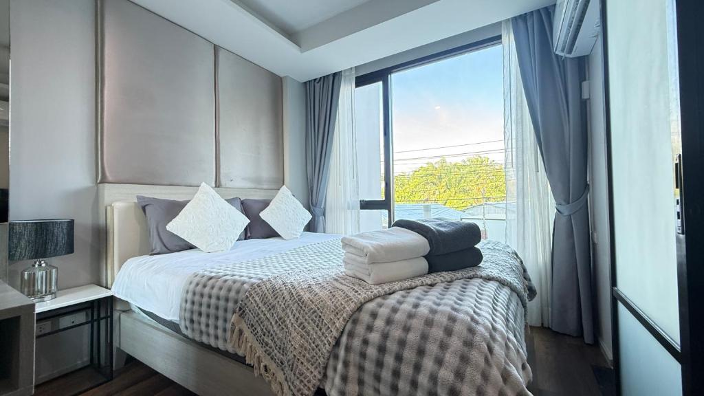 a bedroom with a bed with a large window at 6th Avenue Surin by Win217 in Surin Beach