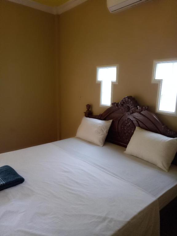 um quarto com uma grande cama branca e 2 janelas em 4R Bungalow em Gili Air