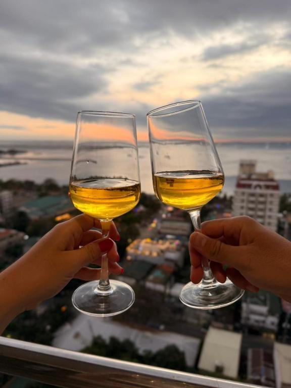 two people holding glasses of wine on a balcony at STAYLUXIA - MANILABAYVIEW - Luxury and Superior Suites with, Balcony -except Studios- Pool, Netflix & Gym- Housekeeping Available - in Manila