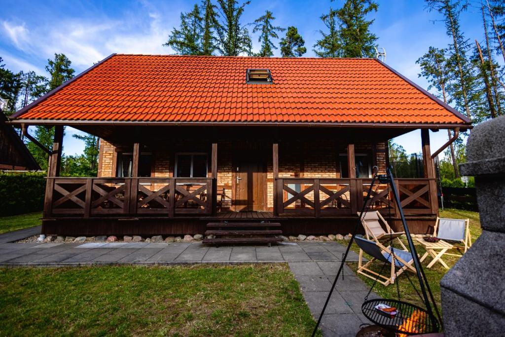 a log cabin with an orange roof at Ceglana Przystań na Kaszubach in Załakowo