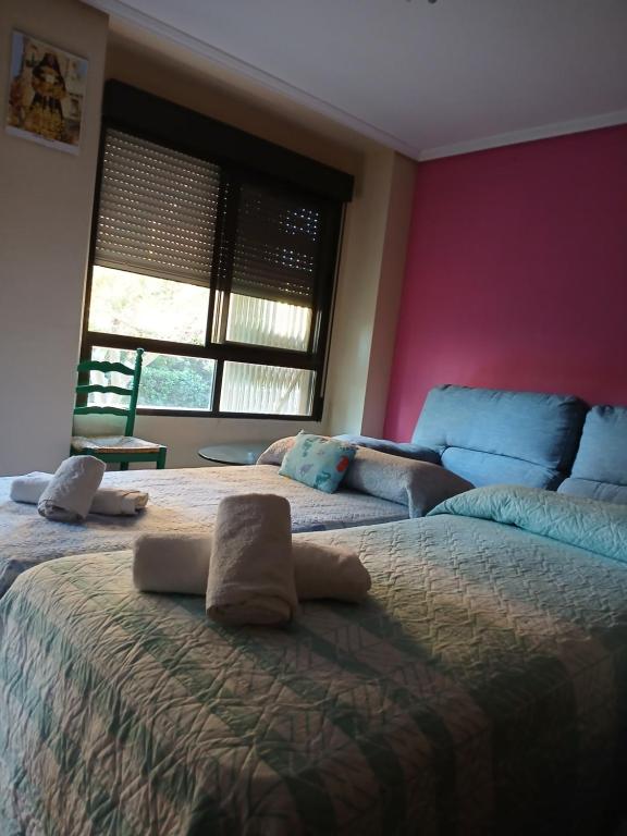 a bedroom with two beds and a pink wall at Habitaciones Castellon in Castellón de la Plana
