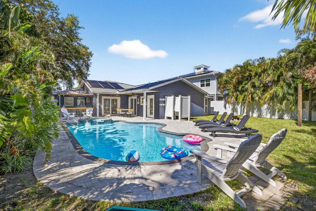 a backyard with a swimming pool with chairs and a house at Steps to beachTiki BarHeated Poolfun! in Clearwater Beach