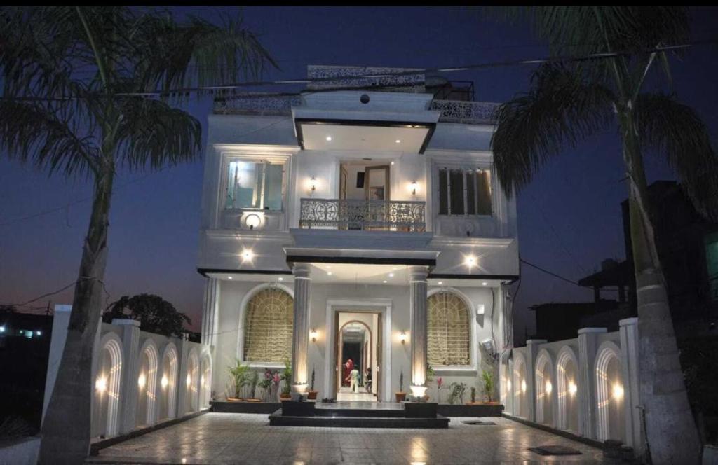 a large white house with a porch at night at Hotel Classio Ali Asgar in Jaorā