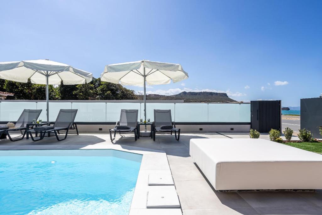 a patio with a pool and chairs and umbrellas at AZURE Seaside Residence in Kokkini Khanion