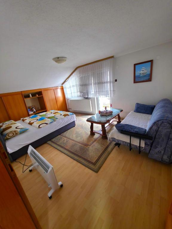 a bedroom with two beds and a couch and a table at Stan na dan Cazin in Cazin