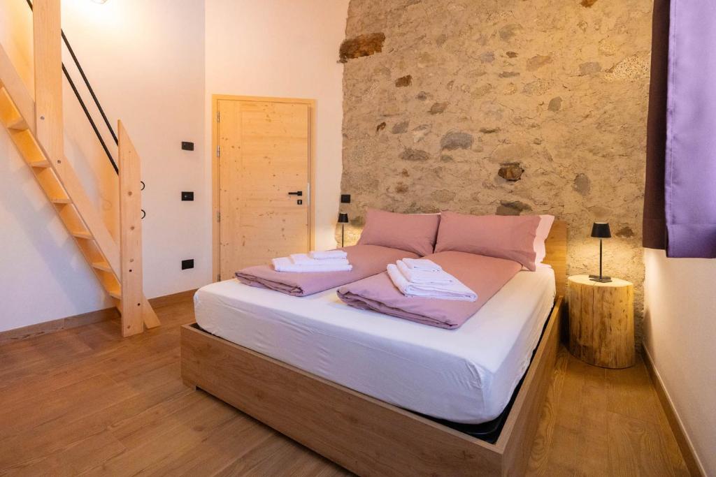a large bed in a room with a stone wall at Country Life Chalet in Tione di Trento