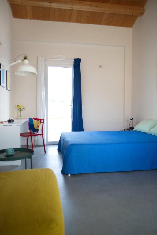 a bedroom with a blue bed and a window at Petrikore - Rosso in Scoglitti