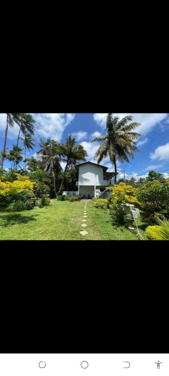a house with palm trees in the middle of a field at Ceylon Sungarden in Habaraduwa Central
