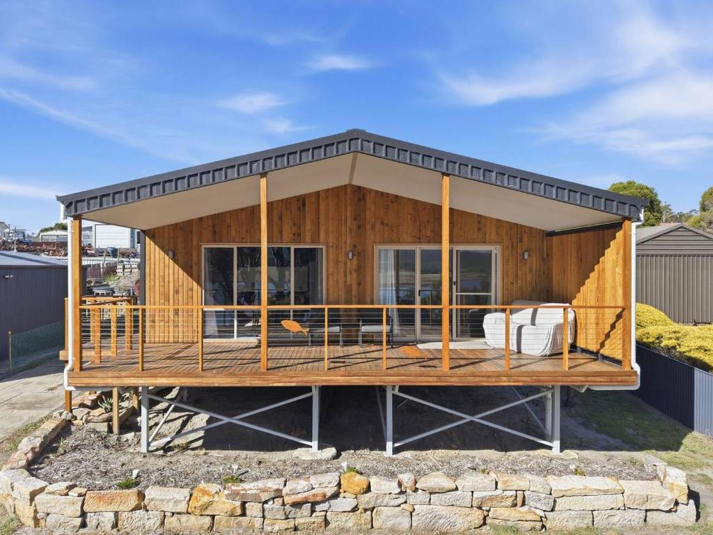 a house with a large deck on top at Tranquil Escape by the Water in Triabunna