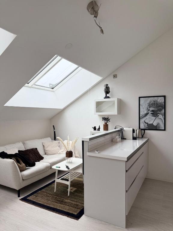 a white living room with a couch and a skylight at Penthouse Studio in Stockholm