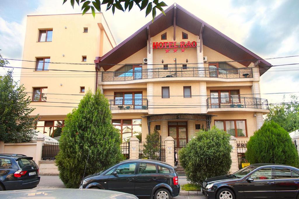 un edificio con coches estacionados frente a él en Hotel Rao en Cluj-Napoca