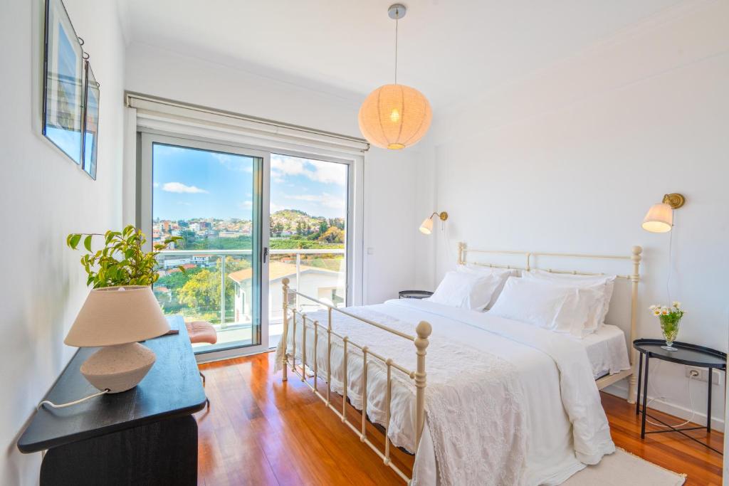 a white bedroom with a bed and a large window at Pátio da Achada View Apartment in Funchal