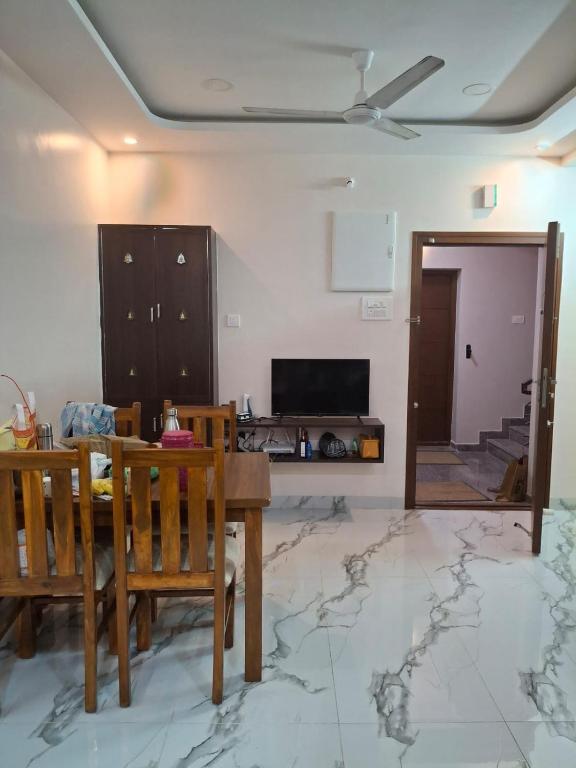 a living room with a table and chairs and a tv at SUMATHY GIRLS HOSTEl in Chennai