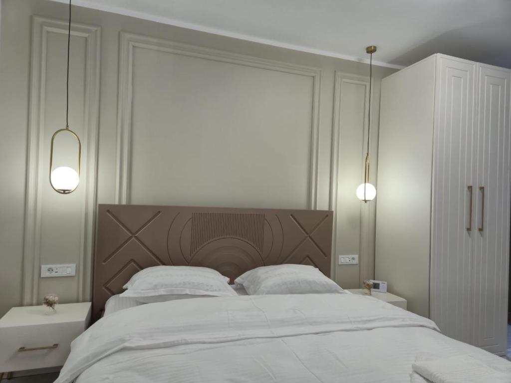 a white bedroom with a large bed with white sheets at Edward Luxury Studio in Slănic-Moldova