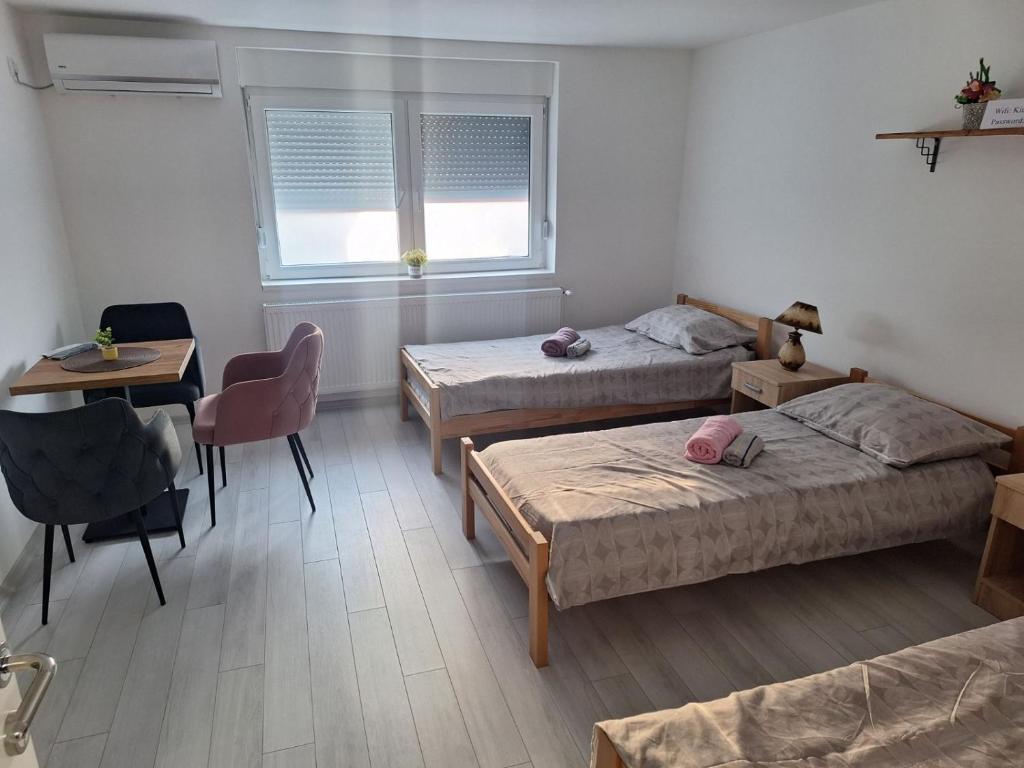 a room with three beds and a table and a desk at King Rooms in Novi Kneževac