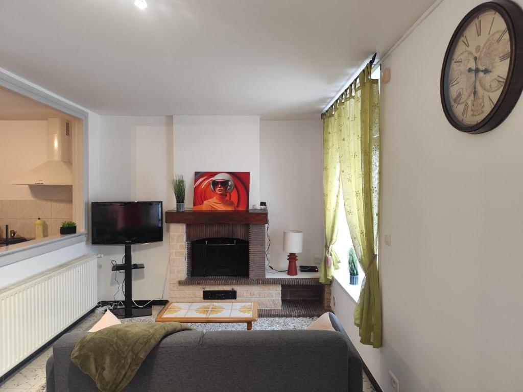 a living room with a couch and a clock on the wall at Appart 2 Ch Bollezeele in Bollezeele