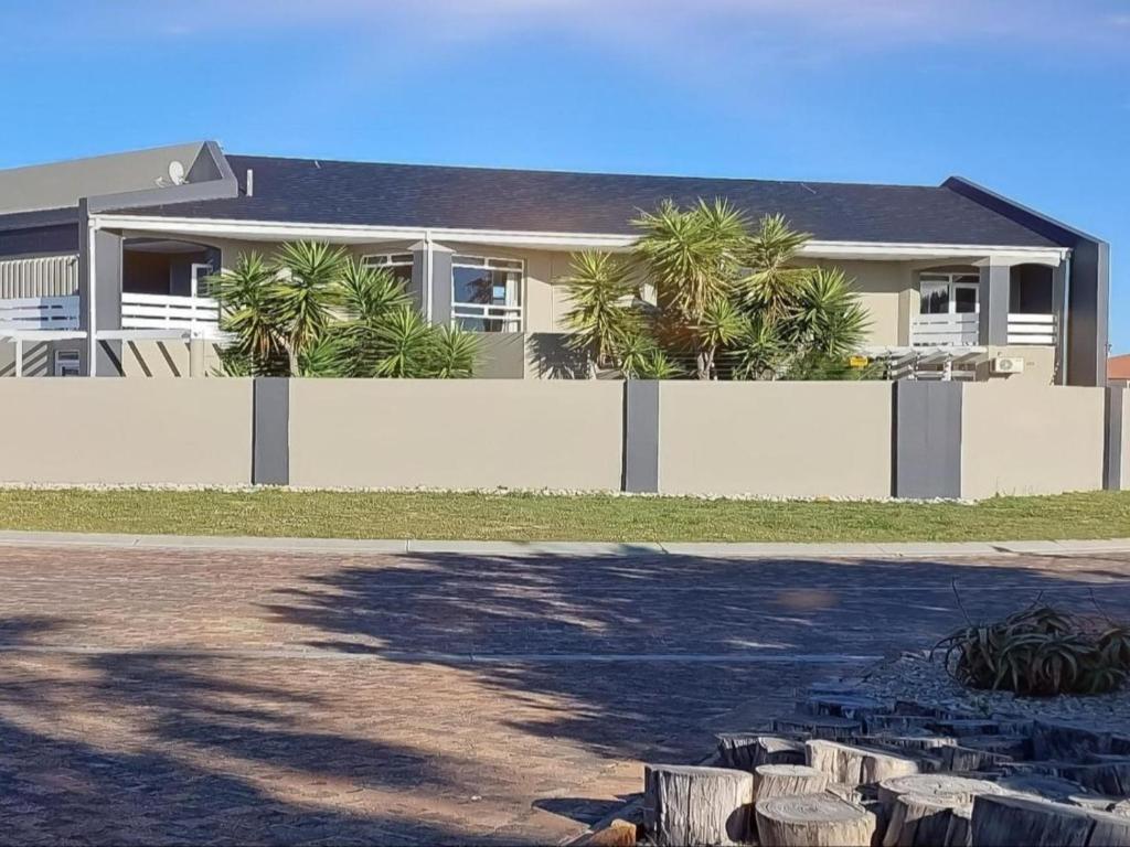 a house with palm trees behind a white fence at Beachwood Inn Melkbosstrand in Cape Town