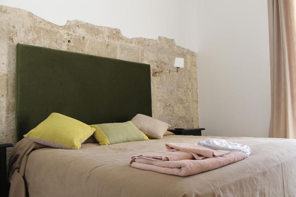 a bed with a green headboard and a blanket on it at Torre Tresca B&B in Bari