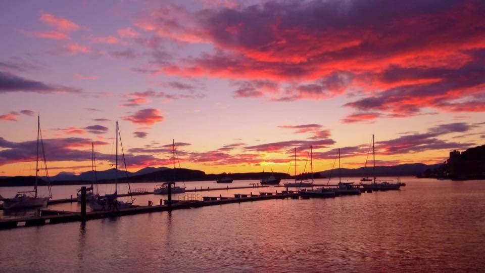 a sunset over a marina with boats in the water at Alexandra Apartment - stunning view in Oban