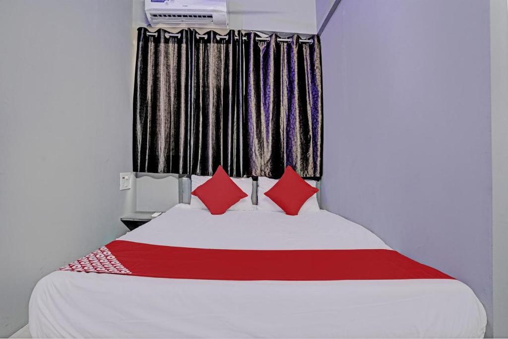 a bedroom with a white bed with red pillows at The Bull Group International in Surat