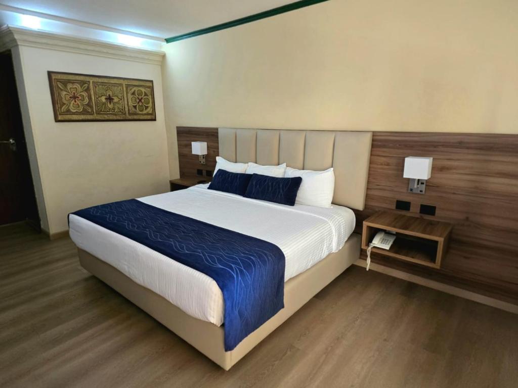 a bedroom with a large bed with a blue blanket at Las Misiones Hotel in Monclova