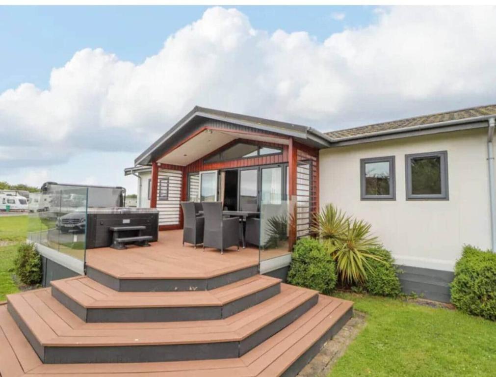 a house with a deck with a grill at Honeysuckle lodge in Abergele