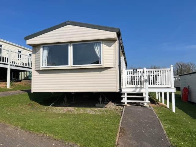 a small white house with a porch and a staircase at Devon Cliff Breaks in Exmouth