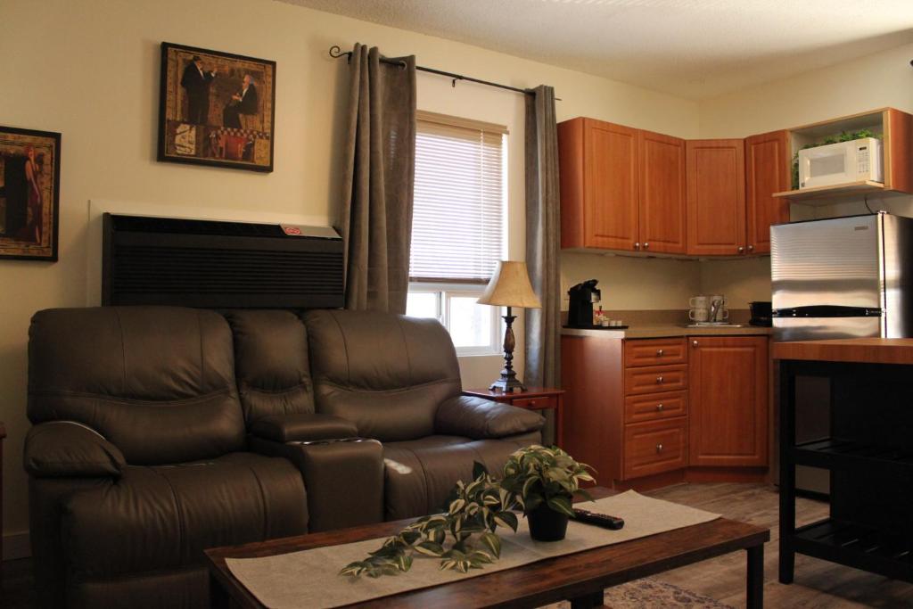 a living room with a leather couch and a kitchen at Royal Duke Hotel in Okotoks