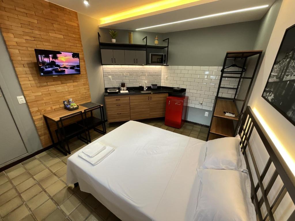a small room with a bed and a kitchen at Studio moderno com ar condicionado central in Aracaju