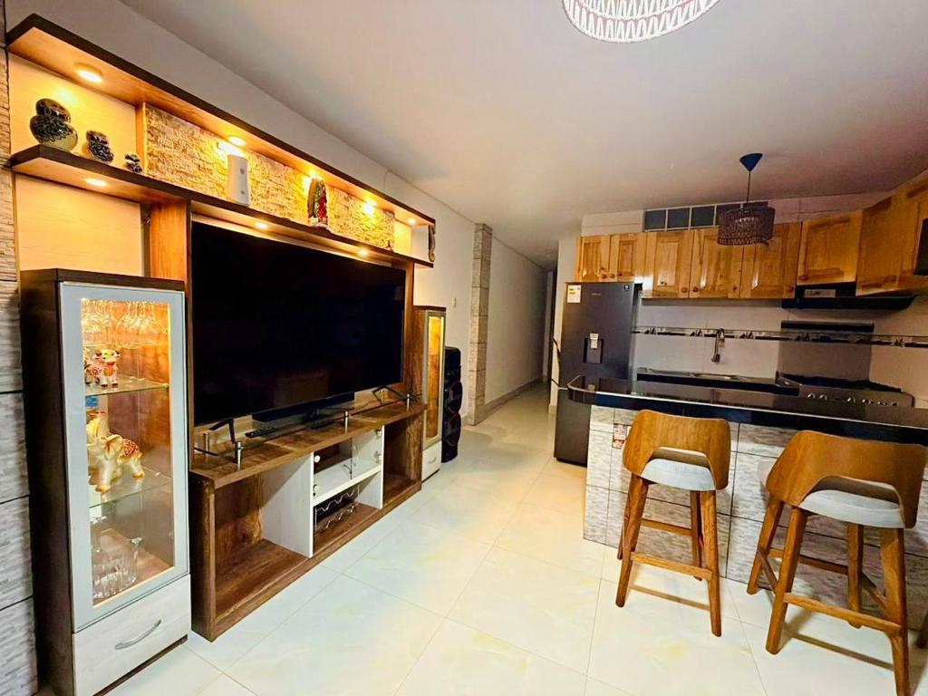 a kitchen with a large flat screen tv and some chairs at Casa 1er Piso in Punta Hermosa