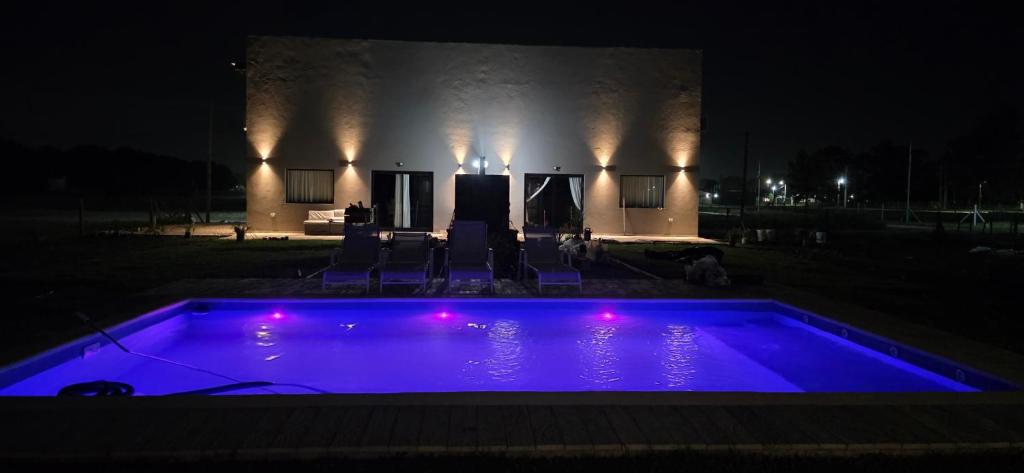 a swimming pool lit up at night with purple lights at Oasis Atlántida in Santa Clara del Mar
